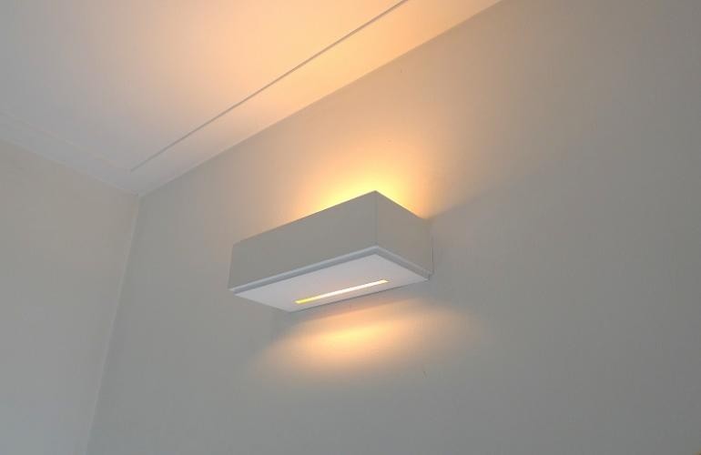 Moderne wandlamp met sfeerverlichting, die vooral het plafond verlicht.