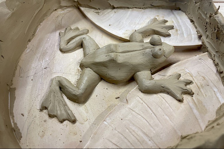 Close-up van handgemodelleerde kikker tijdens het maken van de Art Nouveau rozet