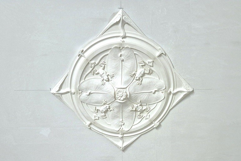 Art Nouveau rozet met waterleliebladeren en kikkers geplaatst aan het plafond